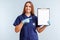 Female doctor pointing at blank paper on clipboard on blue background
