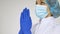 Female doctor is praying wearing protective blue gloves isolated on white background preparing for some medical