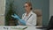 Female doctor preparing for procedure, applying latex gloves indoors