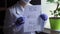 Female doctor in protective mask and suit slowly showing sheet of paper with text: you will all die. Virologist lift up