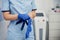 A female doctor puts blue medical gloves on her hands. A doctor in a blue medical suit