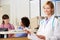 Female Doctor Reading Patient Notes At Nurses Station