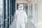 Female doctor scientist in lab coat, defensive eyewear and mask standing indoors with antibacterial spray