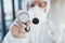 Female doctor scientist in lab coat, defensive eyewear and mask standing indoors and holds stethoscope