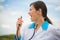 Female doctor singing in stethoscope over blue sky