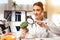 Female doctor sitting at desk in office with microscope and stethoscope. Woman is looking at broccoli with magnifyer.