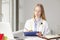 Female doctor sitting and writing in clinic.