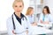 Female doctor smiling on the background with patient and his physician in hospital