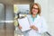 Female doctor smiling, holding optimistic results of diagnosis on clipboard, blank card for print, copy space for text