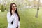 Female doctor speaking on mobile phone . medical background copy space . outdoors of a hospital in flower garden . Cheerful young