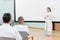 Female doctor is standing in front of a empty whiteboard giving