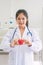 Female doctor with stethoscope holding red heart at hospital office. Medical health care and doctor staff service concept