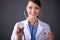 Female doctor with a stethoscope listening, isolated on grey background