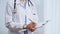 Female doctor taking notes on clipboard. Close-up of a unrecognizable female healthcare professional writing and filling