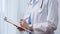 Female doctor taking notes on clipboard. Close-up of a unrecognizable female healthcare professional writing and filling