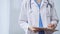 Female doctor taking notes on clipboard. Close-up of a unrecognizable female healthcare professional writing and filling