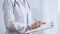 Female doctor taking notes on clipboard. Close-up of a unrecognizable female healthcare professional writing and filling