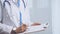 Female doctor taking notes on clipboard. Close-up of a unrecognizable female healthcare professional writing and filling