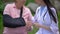 Female doctor talking old lady wearing arm sling, elbow joint injury, fracture