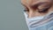 A female doctor therapist in a white robe, mask and gloves. Face close-up. The doctor cries and prays. Tears in eyes