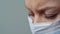 A female doctor therapist in a white robe, mask and gloves. Face close-up. The doctor cries and prays. Tears in eyes