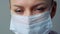 A female doctor therapist in a white robe, mask and gloves. Face close-up. The doctor cries and prays. Tears in eyes