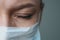 A female doctor therapist in a white robe, mask and gloves. Face close-up. The doctor cries and prays. Tears in eyes