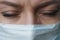 A female doctor therapist in a white robe, mask and gloves. Face close-up. The doctor cries and prays. Tears in eyes