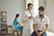 Female doctor in uniform listening to breath of young male patient through stethoscope