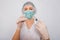 Female doctor in a white coat, medical cap, mask and gloves works with a syringe needle and a medical ampoule. A scientist in ster