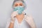 Female doctor in a white coat, medical cap, mask and gloves works with a syringe needle and a medical ampoule. A scientist in ster