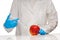 Female doctor in white medical gown and blue sterilized surgical gloves makes injection to bad looking apple with plastic syringe