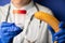 Female doctors hands in medical blue gloves holding a plastic container with sperm and a banana