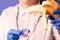 Female doctors hands in medical blue gloves holding a plastic container with sperm and a banana