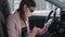 female driver inside car is sending message by smartphone, woman is wearing mask