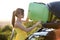 Female driver putting green suitcase inside her car roof trunk. Travel and vacations concept