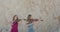 Female duet of violinists in blowing dresses play music on cliff background
