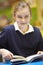 Female Elementary School Pupil Reading Book In Classroom