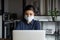 Female employee in face mask work on laptop in office