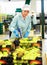 Female employee of fruit warehouse in uniform labeling fresh ripe apples in crates