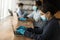 Female employee in medical gear work on computer in office