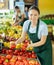 Female employee was distracted for minute and stands smiling with ripe tomato in hands
