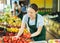 Female employee was distracted for minute and stands smiling with ripe tomato in hands