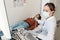Female endocrinologist in whitecoat and mask sitting by ultrasound equipment