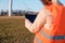 Female engineer checking or repairing wind mills or wind turbines using a tablet in an orange vesta.