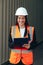 Female Engineer with Clip Folder in white helmet and vest working in container terminal port or construction site