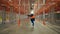 Female engineer dances on aisle between empty metal racks