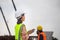 Female engineer and foreman worker checking project at building site, Engineer and builders in hardhats discussing on construction