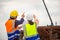 Female engineer and foreman worker checking project at building site, Engineer and builders in hardhats discussing on construction