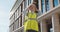 Female engineer in hardhat making video call to client standing outdoors at construction site